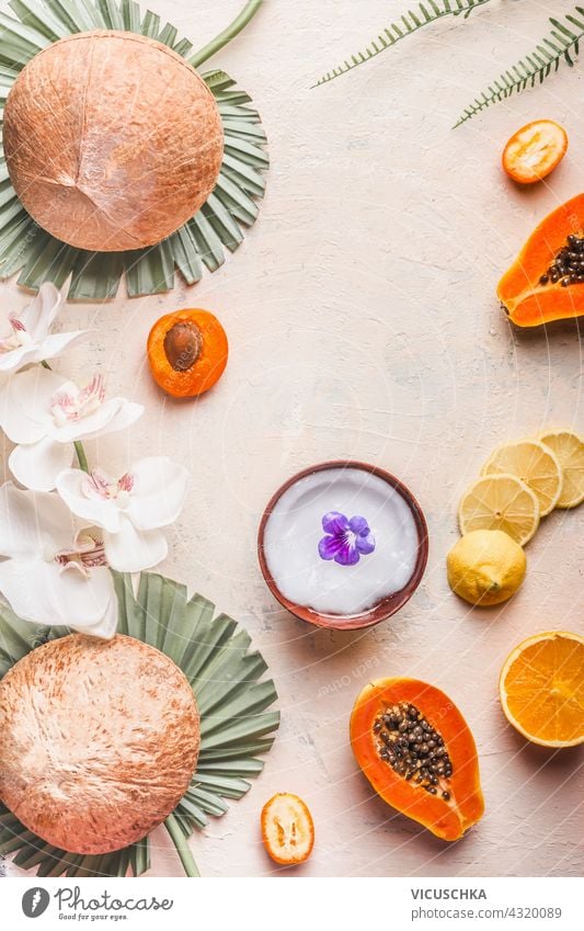 Coconut oil in a coconut shell and tropical fruits are arranged in a frame on a light table. Healthy lifestyle coconut oil healthy background cosmetic nutrition