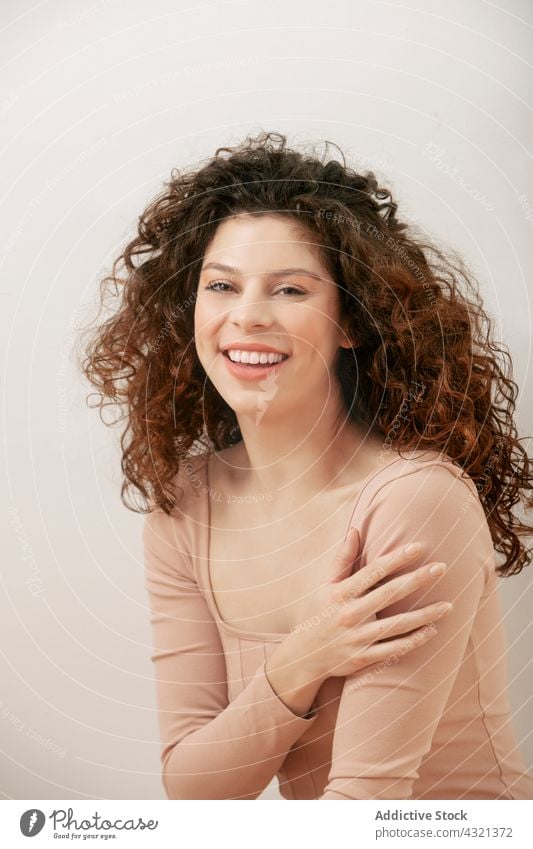 Delicate woman in beige bodysuit in studio tender grace pastel color charming gentle female style outfit curly hair slender sit floor slim feminine calm