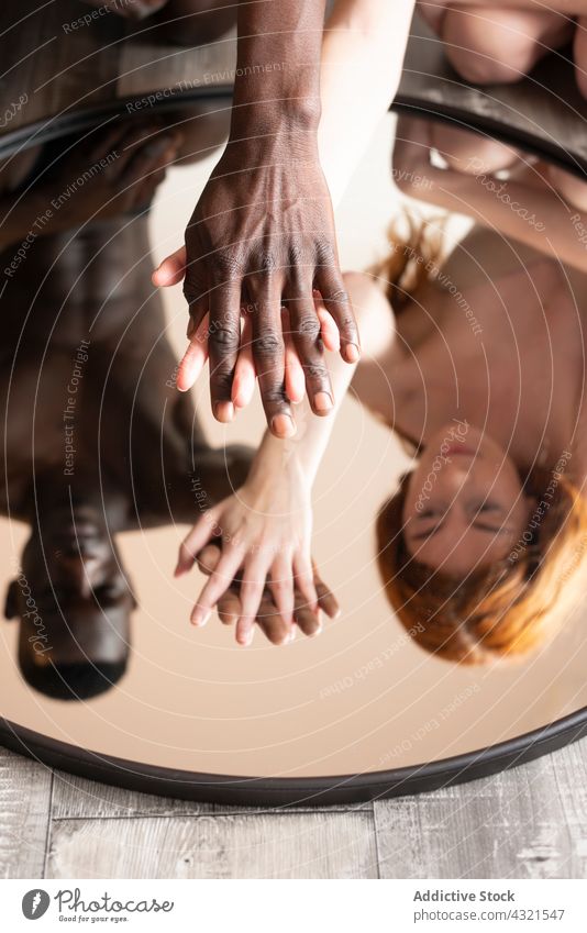 Multiracial couple holding hands and reflecting in mirror tender love reflection relationship touch gentle together multiethnic multiracial diverse black