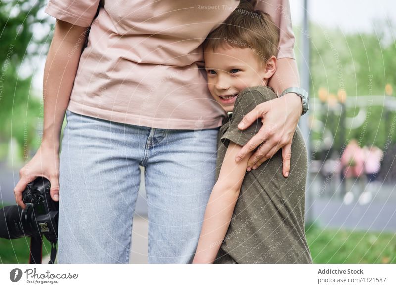 Crop mother and son hugging together embrace child cheerful parent boy love park kid happy cute smile summer motherhood content affection cuddle glad enjoy