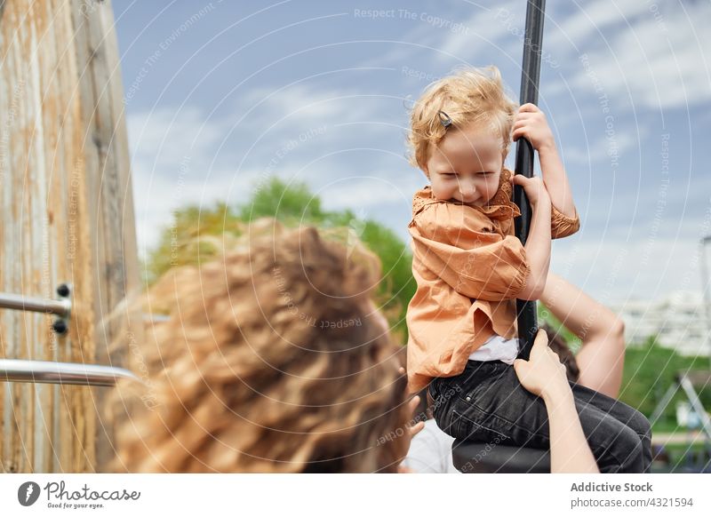 Cute child riding rope swing on playground with mother entertain kid together happy having fun girl childhood park cheerful daughter joy enjoy activity playful