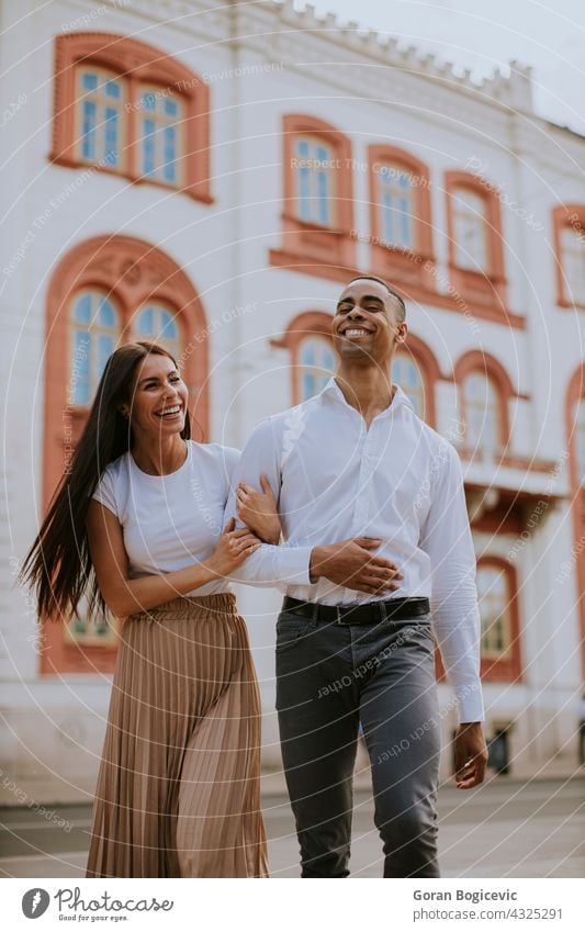 Young multiethnic couple walking on the street love woman young happy relationship together people urban romance city caucasian beautiful embracing female