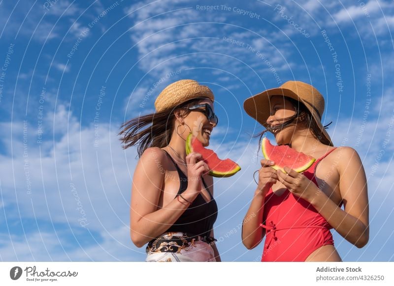 Smiling women in swimsuits and with watermelon against blue sky summer vacation holiday friend together smile sunny female cheerful happy friendship enjoy