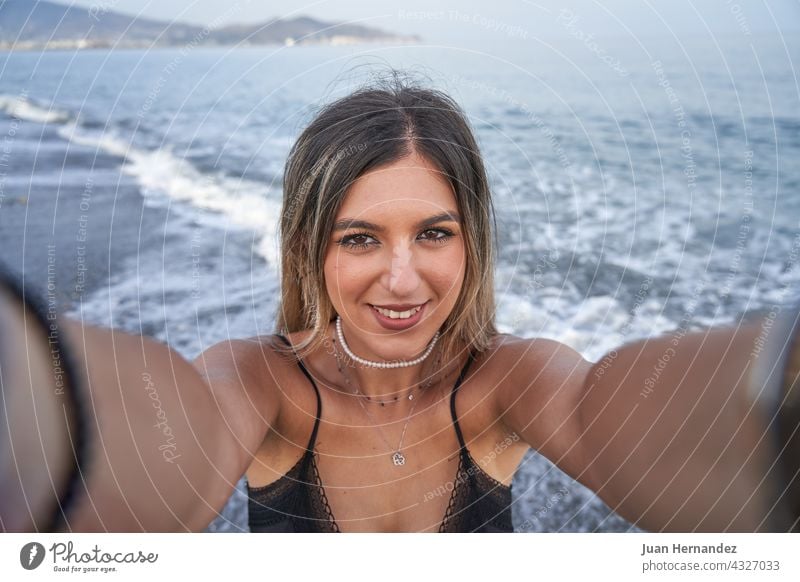 young woman takes a selfie with the mobile and the sea in the background pretty smart phone smartphone photo picture lady smile nice beauty posing mobile phone