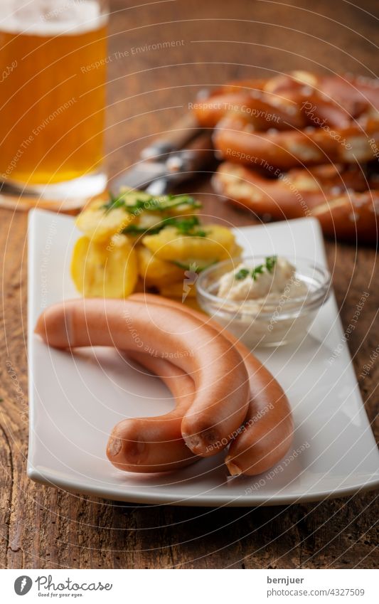 Frankfurter sausages on rustic wood Small sausage sauce Radish horseradish Hot three potato salad Lettuce Bavarian Vienna background White Plate rectangular Raw