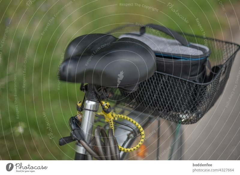 a bicycle parked on the cycle path with a view of the saddle and the bicycle basket containing a camera bag Cycling tour photo safari Bicycle Saddle Fre