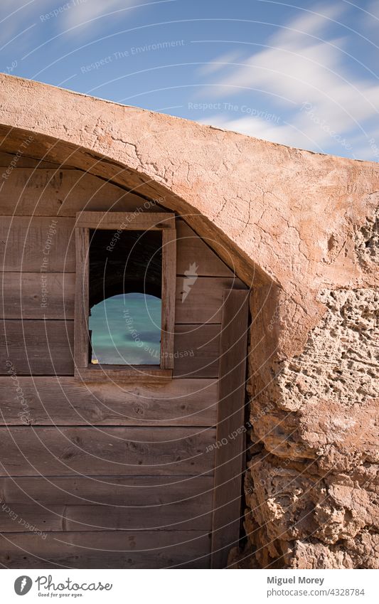 Window in an old abandoned fisherman's boat house by the sea. Ocean Vacation & Travel Relaxation boathouse seaside mediterranean Water Mediterranean sea Horizon