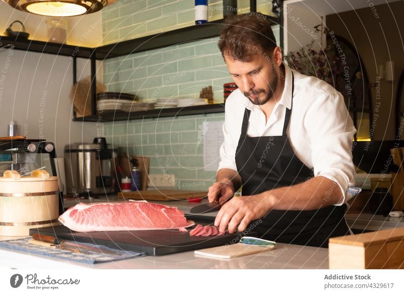 Male cook cutting fish in kitchen of restaurant chef sushi seafood man oriental fresh male prepare meal table gourmet cuisine asian food professional culinary