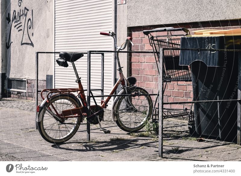 old folding bike at the bike stand Bicycle Folding bicycle Bicycle rack turnaround City life Shopping Trolley dustbin roller shutter Town Shadow