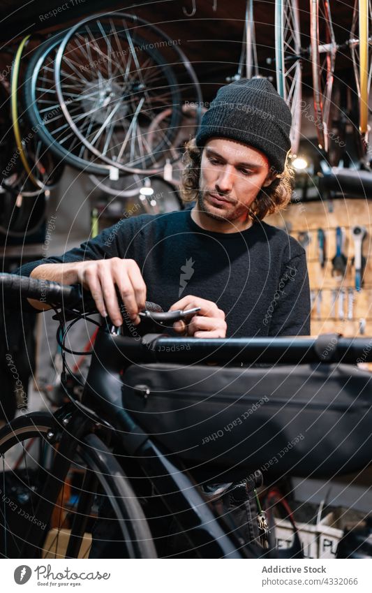 Focused man repairing bike in workshop fix bicycle mechanic handlebar service master male garage busy tool vehicle job professional transport maintenance