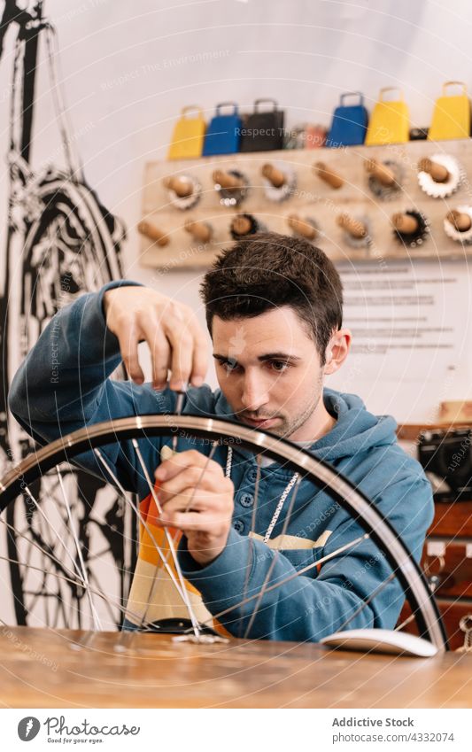 Man repairing bicycle wheel in workshop man fix spoke rim mechanic bike male service workbench master garage busy tool vehicle job professional transport