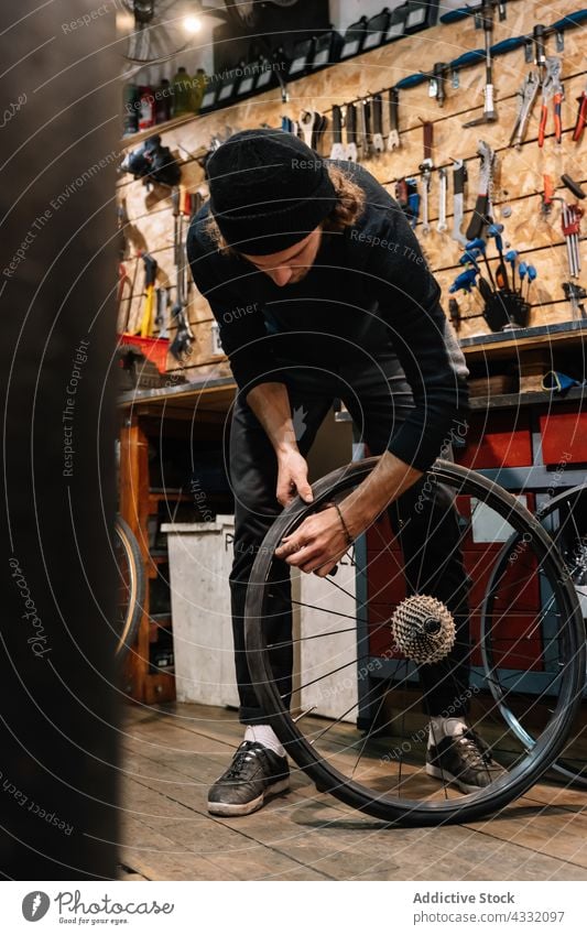 Focused man fixing bike in garage bicycle wheel workshop repair mechanic repairman male service vehicle job professional transport busy tool maintenance