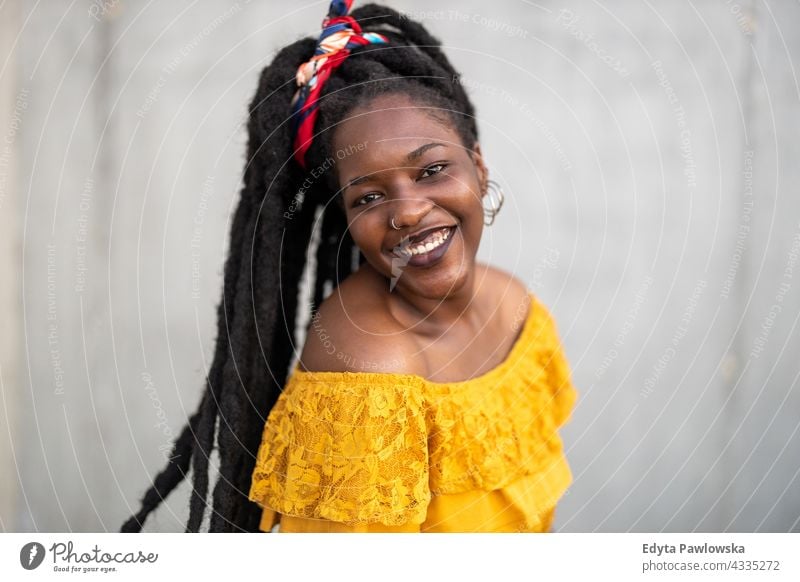 Beautiful young woman with dreadlocks in front of gray wall proud real people city life African american afro american Black ethnicity sunny sunset outside girl