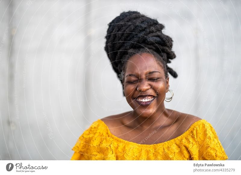 Joyous woman in front of wall dreadlocks proud real people city life African american afro american Black ethnicity sunny sunset outside girl one person adult