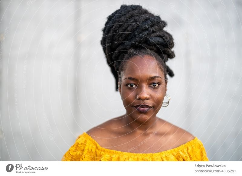 Beautiful young woman with dreadlocks in front of gray wall proud real people city life African american afro american Black ethnicity sunny sunset outside girl