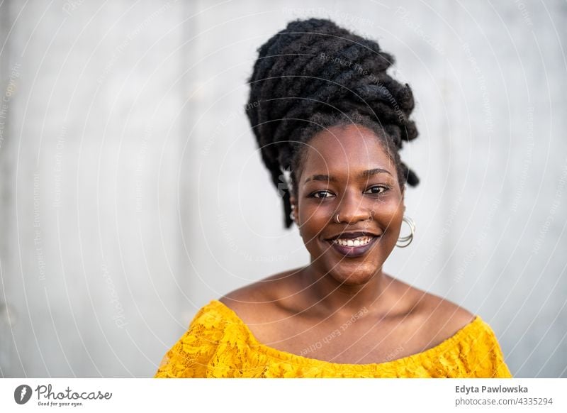 Beautiful young woman with dreadlocks in front of gray wall proud real people city life African american afro american Black ethnicity sunny sunset outside girl