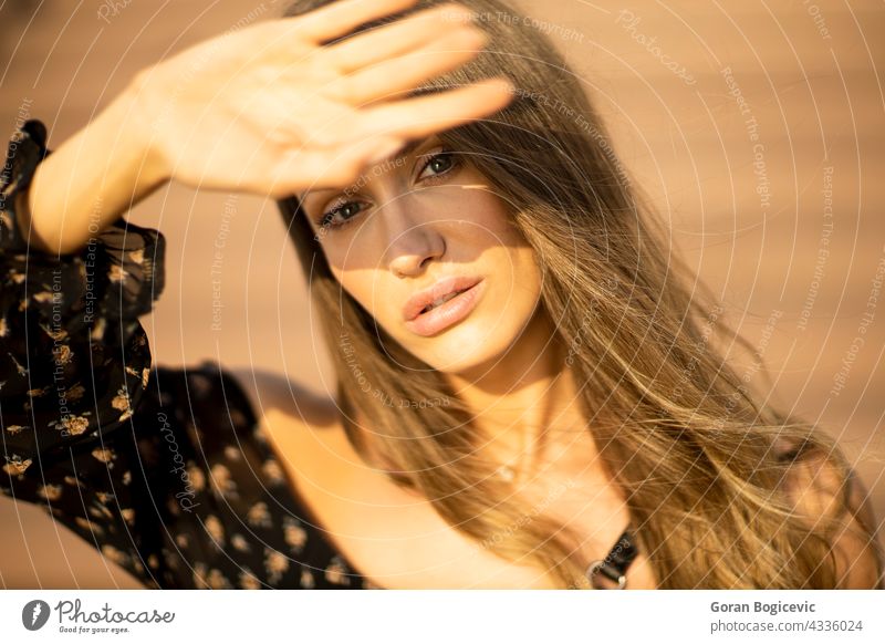 Outdoor portrait of sensual long hair brunette female covering her face with hand from sunlight adult attractive beautiful beauty casual caucasian closeup