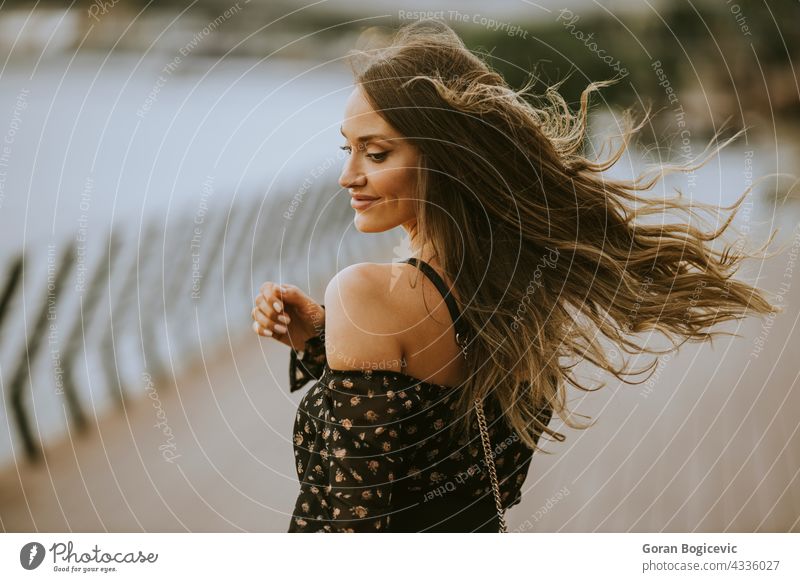 Young long hair brunette woman walking on the riverside caucasian person portrait dress beauty smile beautiful model female young alone pretty lifestyle outdoor