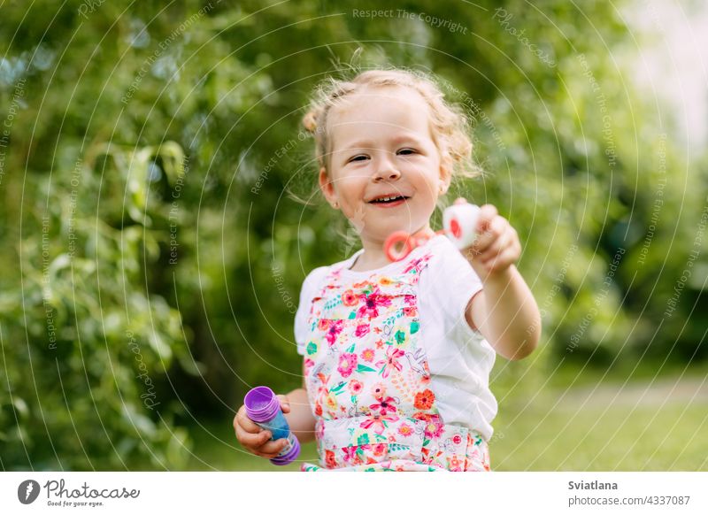 Charming baby girl with soap bubbles in the park or garden little joy childhood green fun portrait blow beautiful kid summer play cute nature funny blowing game