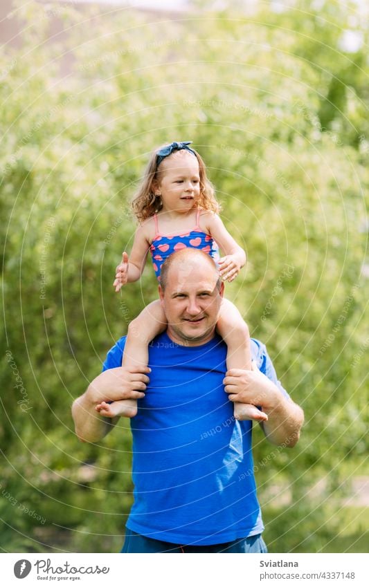 Dad rolls his charming daughter on his neck baby together father girl playing cute child man park family day love happy dad parent happiness little daddy kid