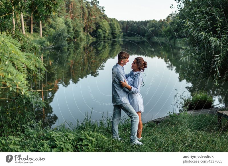 Young couple is hugging and walking near the lake on sunny day. Man and woman on summer holiday. Concept of lovely family. selective focus young sunset romantic