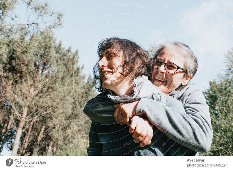 Senior woman and her daughter smiling and having fun on the forest during a sunny day. Happy mother's day joy laughing togetherness happiness people care face