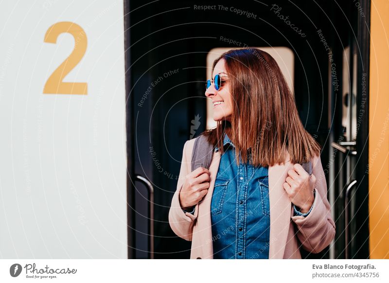 smiling young backpacker caucasian woman standing on wagon at train station. Travel concept mobile phone travel happy technology daytime Porto platform arrival