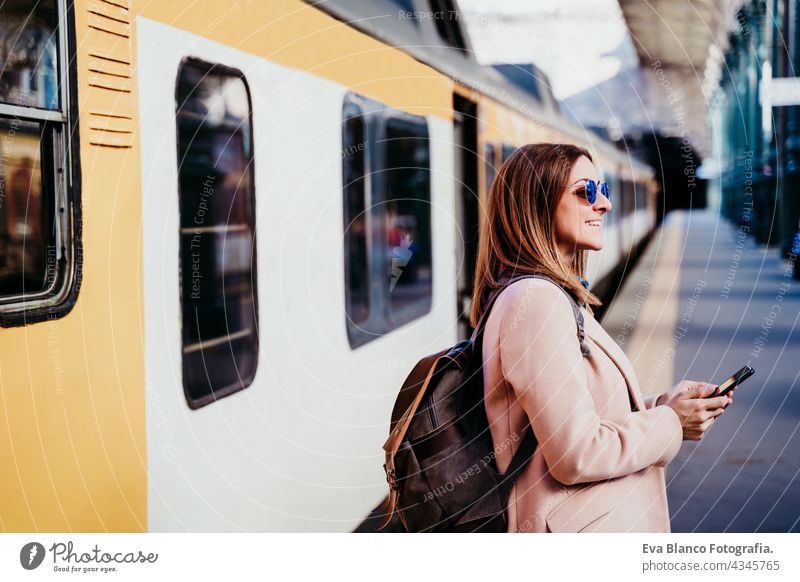 happy backpacker caucasian woman at platform on train station using mobile phone. Travel concept travel technology daytime Porto arrival baggage beautiful board