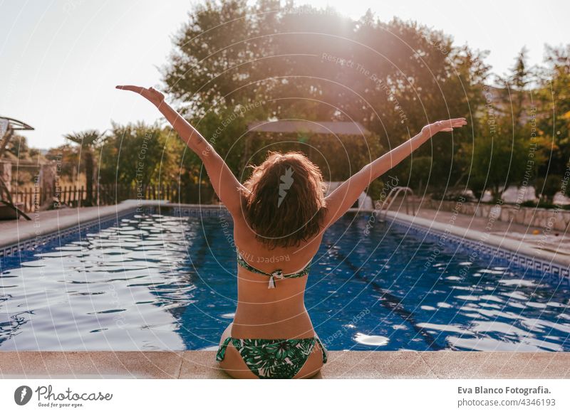 back view of caucasian woman sitting by pool side wearing bikini swimwear. Summer time, vacation and lifestyle swimming pool sunglasses summer hot funny sunny