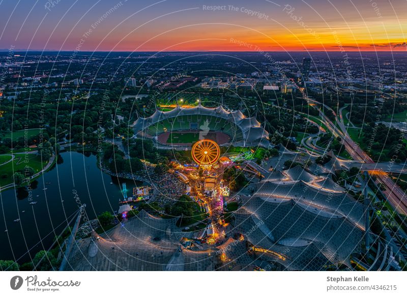 Beautiful Munich sunset from a bird's eye view with a festival in the popular Olympiapark and the stadium in the bright orange twilight. people Festival Above