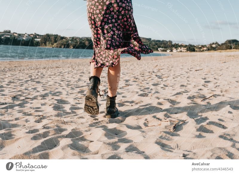 Back shot of a woman walking on the beach during a sunny day with a skirt, copy space, summer concept sand carefree carrying erotic fitness freedom glamour