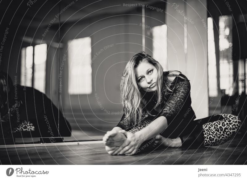 Young beautiful dancer relaxing after workout in ballet/fitness studio | reflection in background in black and white Woman gymnastics dance studio Dance