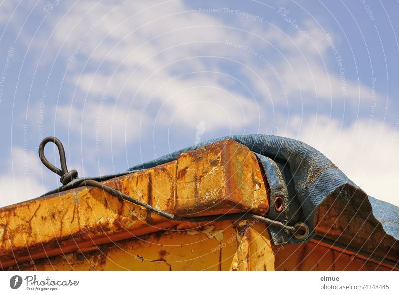 upper corner of orange container with blue tarpaulin in front of light blue sky with fair weather clouds Container Container Corner bins Orange