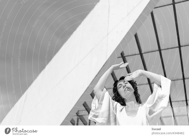 woman with wide sleeves in front of a building with a sculptural facade portrait architecture lines exterior people mature outdoor japanese sleeves lifestyle