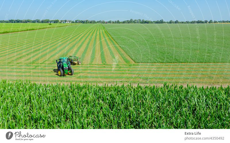 Aerial view of tractor as tow lawn mower machinery behind Above Agriculture Alfalfa Attached Clipper Clover Crop Cut Cutter Drag Farming Farmland Field Grass