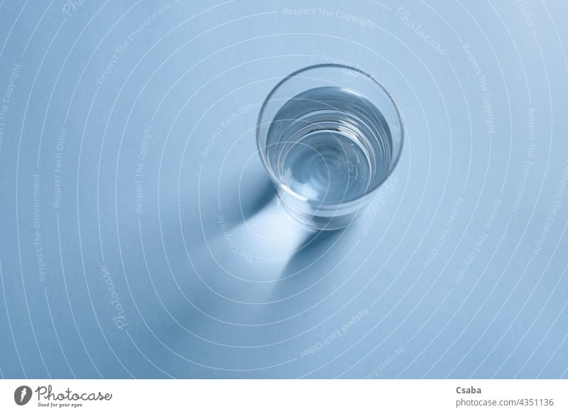 Top view of a glass of clean drinking water on blue background clear top view minimalist beverage liquid transparent reflection purity crystal healthy fresh