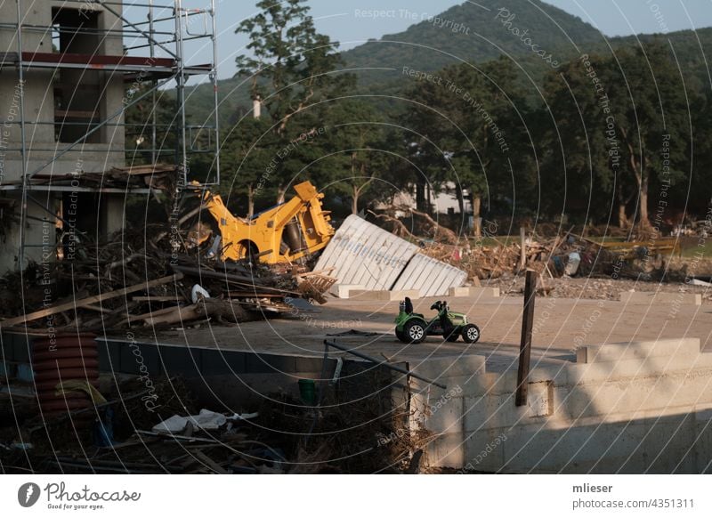 Devastated shell with children electric tractor after flood disaster Tractor children's vehicle children's toy unfinished Foundations devastation Trash