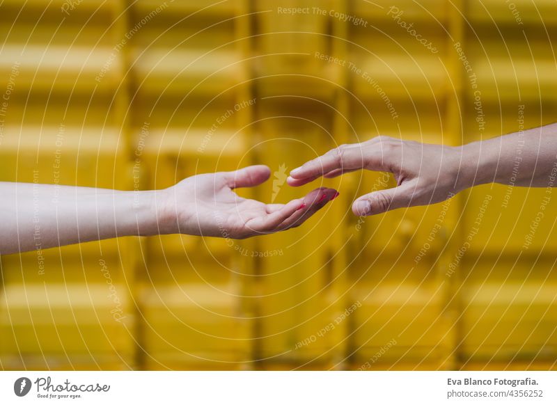 close up of lesbian couple holding hands in front of yellow background. Love is love . LGBTI concept unrecognizable happy caucasian women friends together