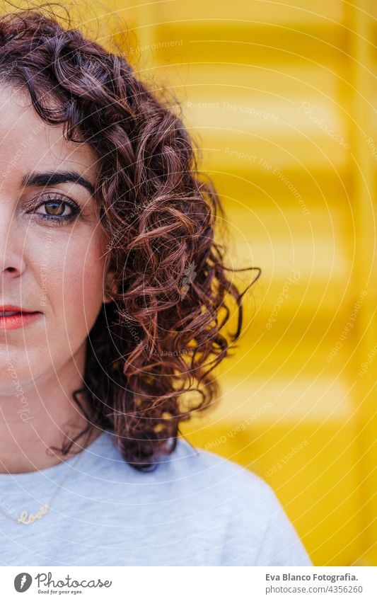 half view of relaxed caucasian woman with curly hair over yellow background. summer time. Outdoors lifestyle happy brunette smiling outdoors city carefree smile