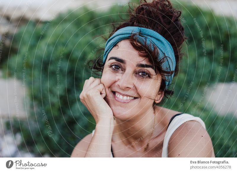 close up portrait of happy caucasian woman smiling in front of green vegetation during summer time. Outdoors lifestyle wall outdoors city beach carefree smile