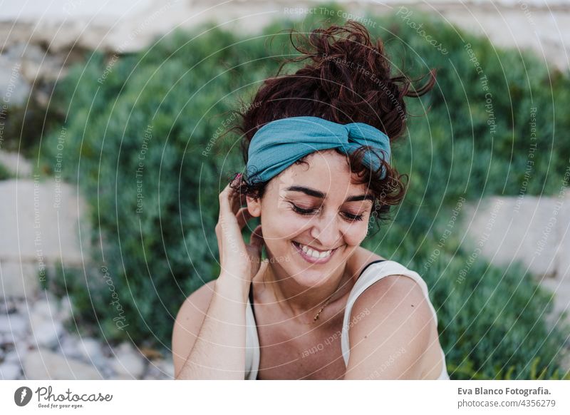 close up portrait of happy caucasian woman smiling in front of green vegetation during summer time. Outdoors lifestyle wall outdoors city beach carefree smile