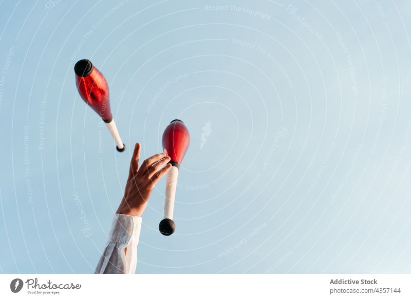 Juggler performing circus trick against blue sky juggle artist club hand entertain talent skill activity show colorful practice stunt amusement motion exercise