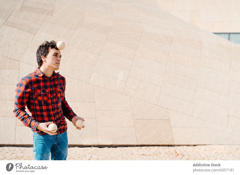 Young man juggling balls near modern building juggle trick perform architecture contemporary geometry entertain talent art skill activity practice male young