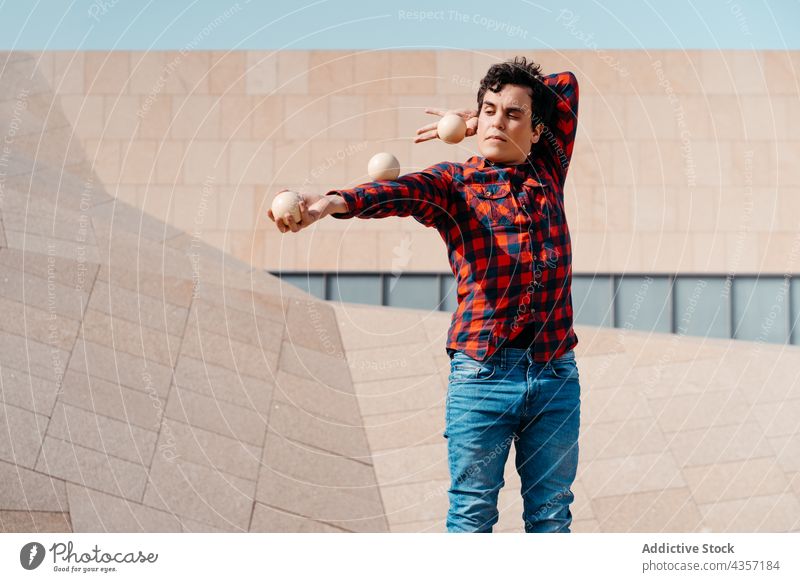 Young man juggling balls near modern building juggle trick perform architecture contemporary geometry entertain talent art skill activity practice male young