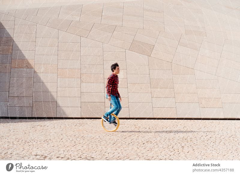 Man riding unicycle near geometric construction man ride modern architecture geometry building wheel urban transport alternative male young contemporary balance