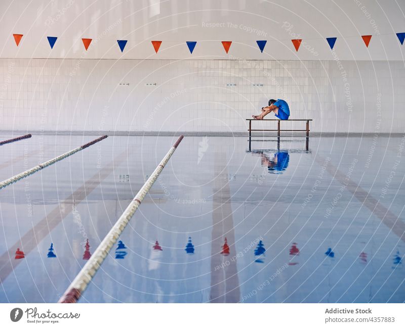 Water aerobics instructor exercising in swimming pool water trainer exercise poolside stretch warm up coach workout training practice fit sit embracing knee