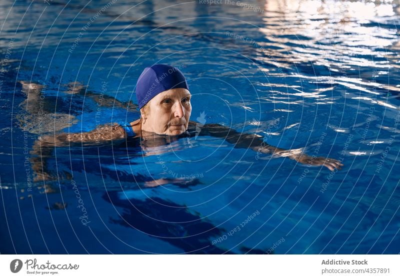 Mature woman swimming in pool during water aerobics mature exercise training swimmer swimsuit female middle age focus concentrate activity body practice clean