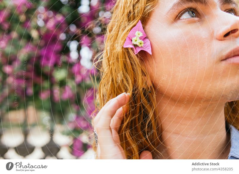 Carefree man with long hair in garden with blooming trees carefree dreamy street summer appearance serene tender male urban curious flower hairstyle daydream