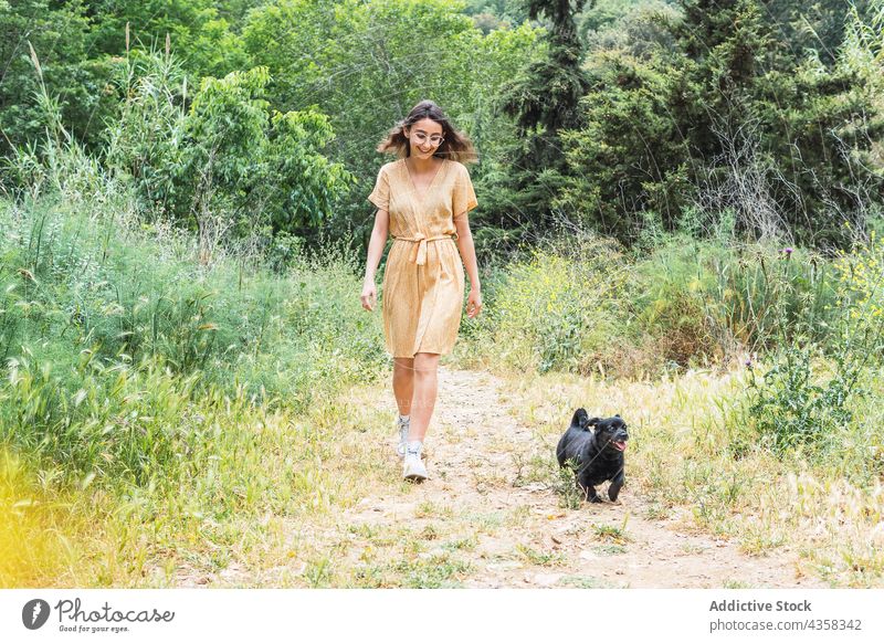 Woman walking with dog in park woman pet summer stroll weekend together carefree female cheerful happy cute friendship canine adorable nature owner joy smile