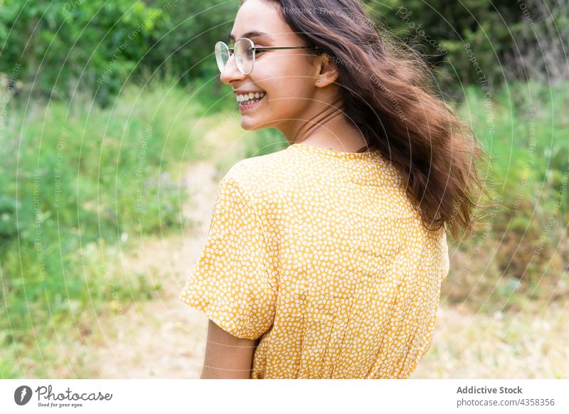 Carefree woman walking in summer park dress smile cheerful carefree enjoy stroll female delight nature style positive charming happy optimist glad weekend green